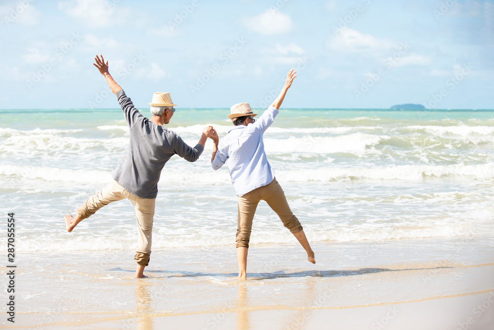 Happy asian senior couple  have fun and enjoy at the beach, senior man and woman hands up on the bea