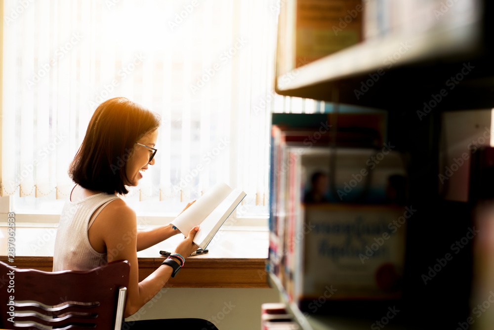 Happy Asia woman  in eyeglasses reading a book at a bookstore,Relaxing lifestyle  healthy education 