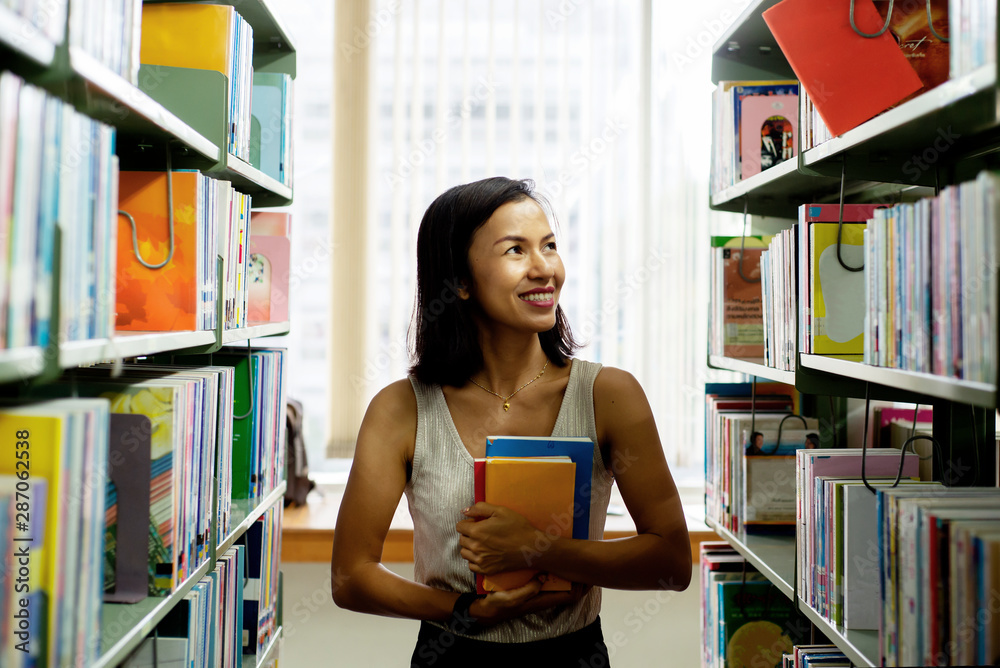 Smilling Asian woman looking a book on bookshelf at library, Relaxing lifestyle  healthy education c