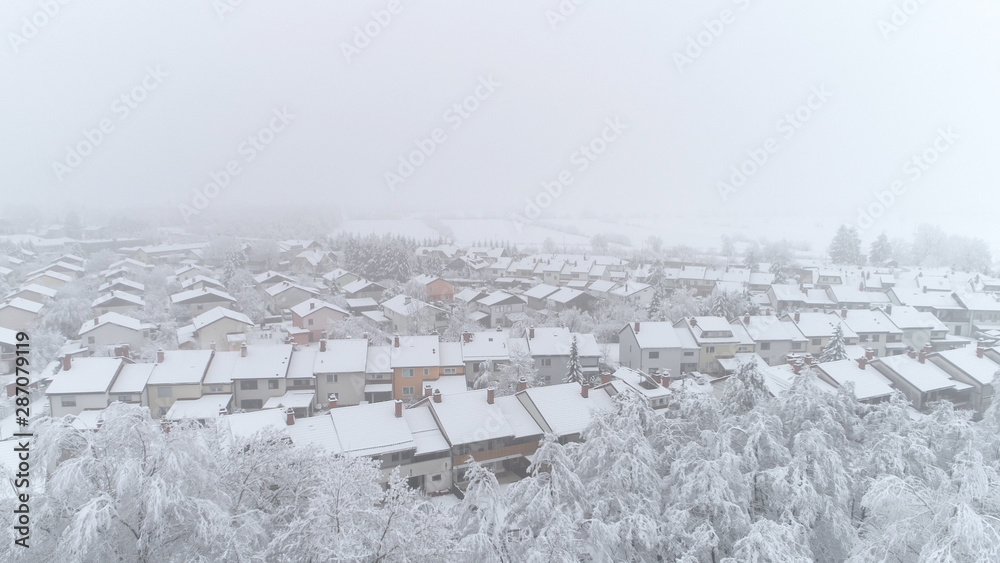 AERIAL: Flying above snowy row houses in peaceful suburban city on winter day