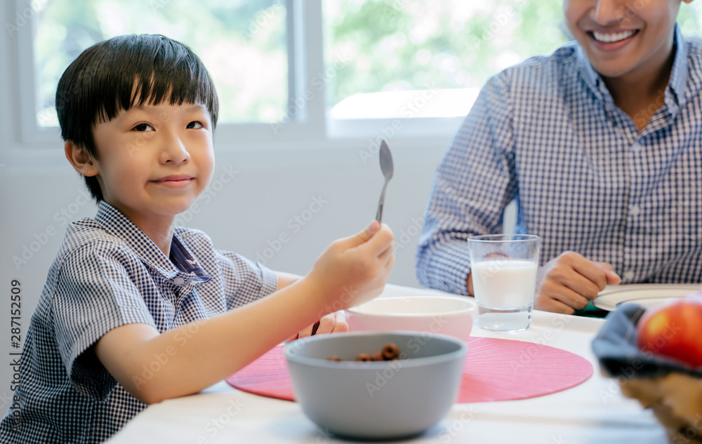 男孩正在家里和家人一起吃早餐。