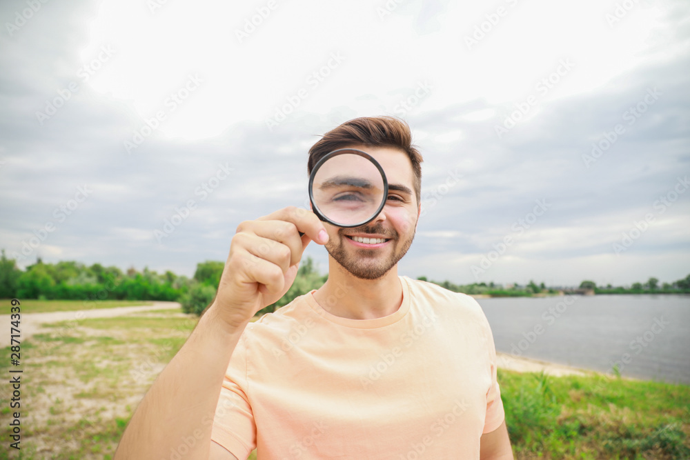 Man with magnifying glass studying nature outdoors