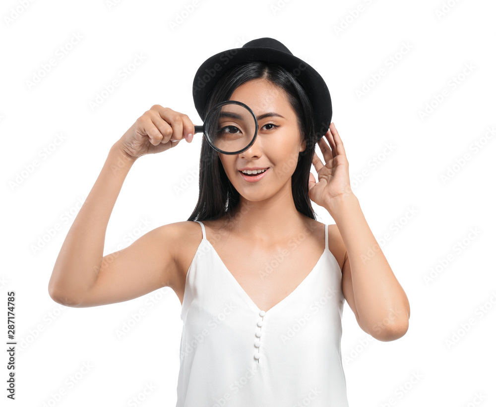 Young Asian woman with magnifying glass on white background