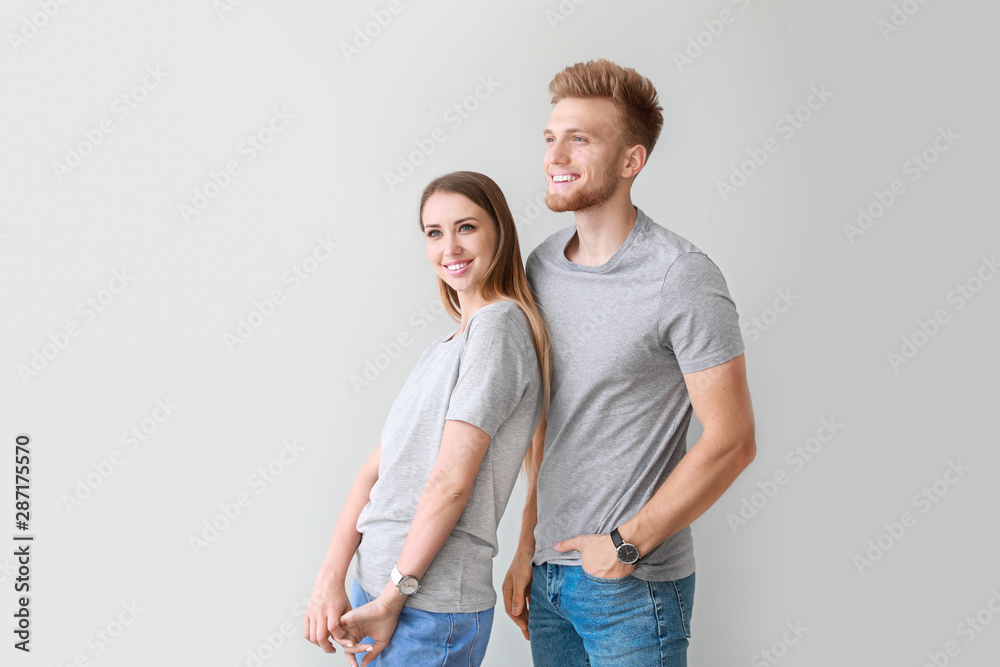 Couple in stylish t-shirts on light background