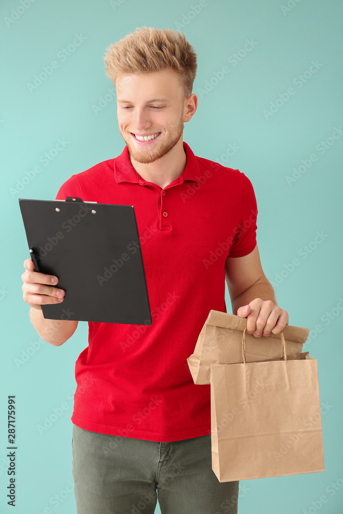 Handsome worker of food delivery service on color background