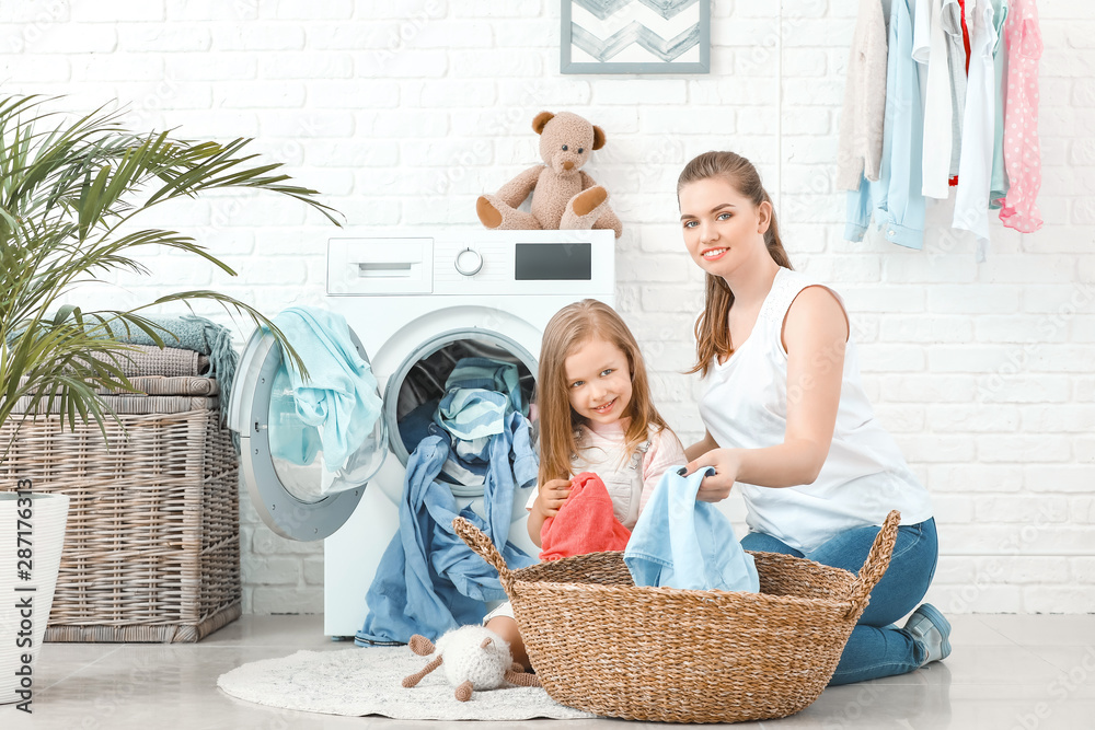 Woman and her little daughter doing laundry at home