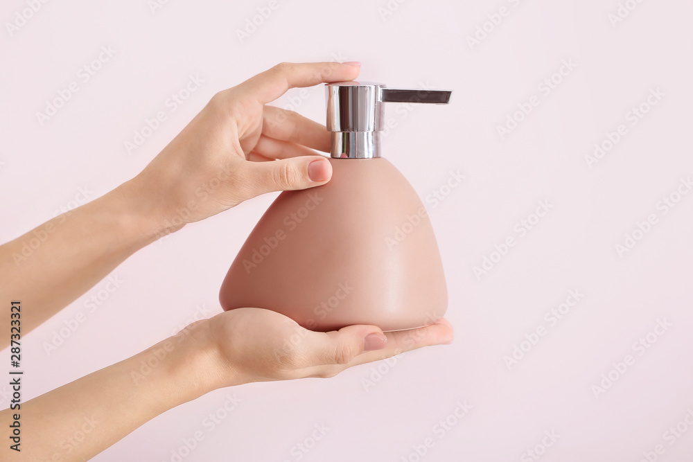 Female hands with soap in bottle on light background