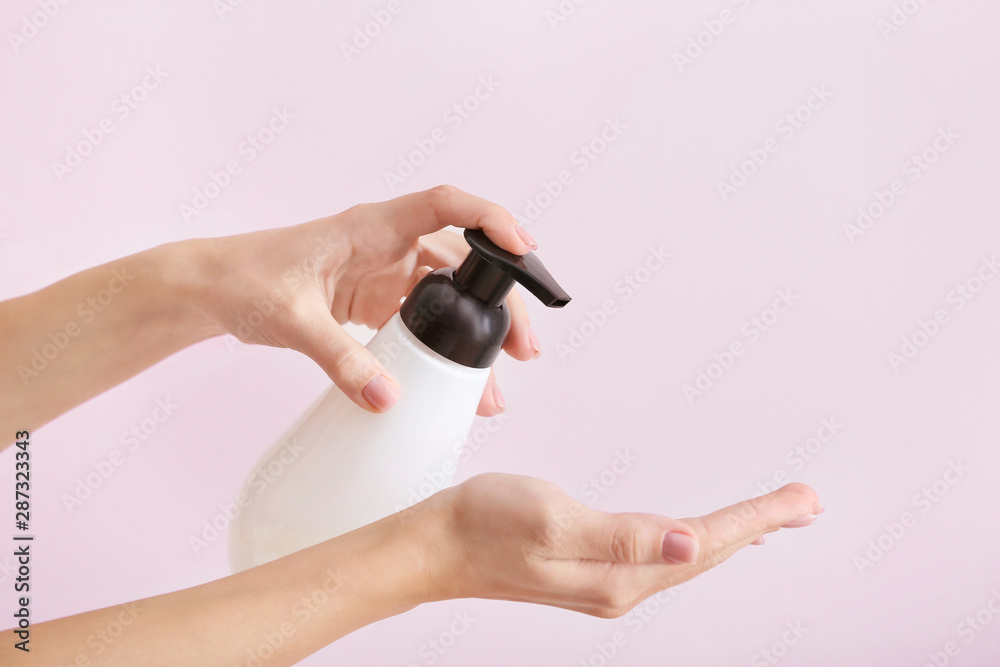 Female hands with soap in bottle on light background