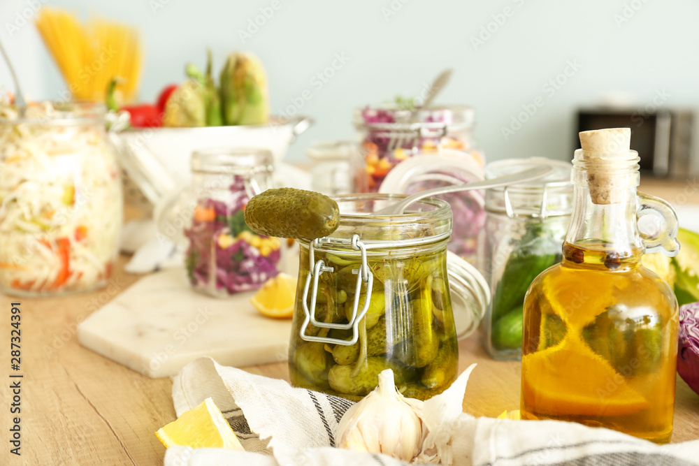 Jar with canned cucumbers on wooden table in kitchen