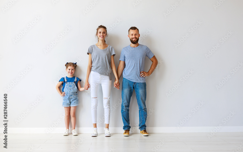 happy family mother father and child  near an empty wall