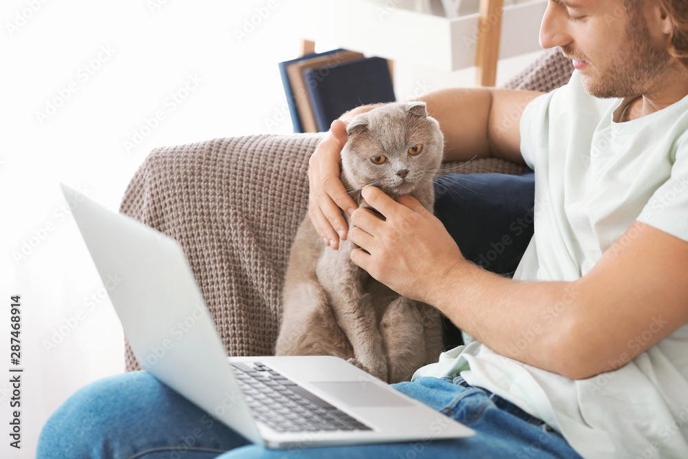 家里有笔记本电脑的男人和可爱有趣的猫