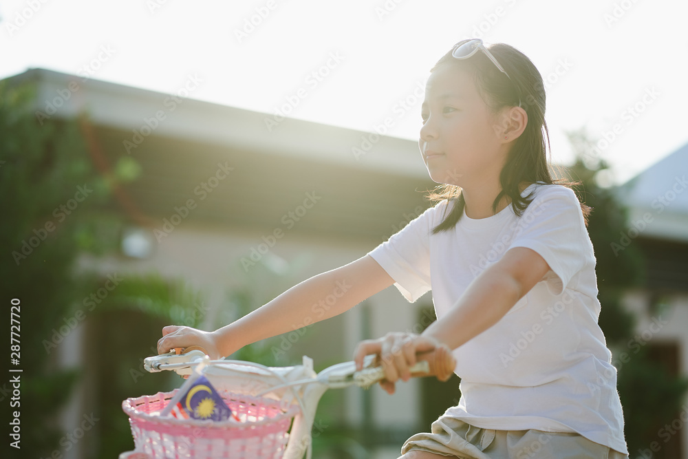 日落时在花园里骑自行车的亚洲小女孩