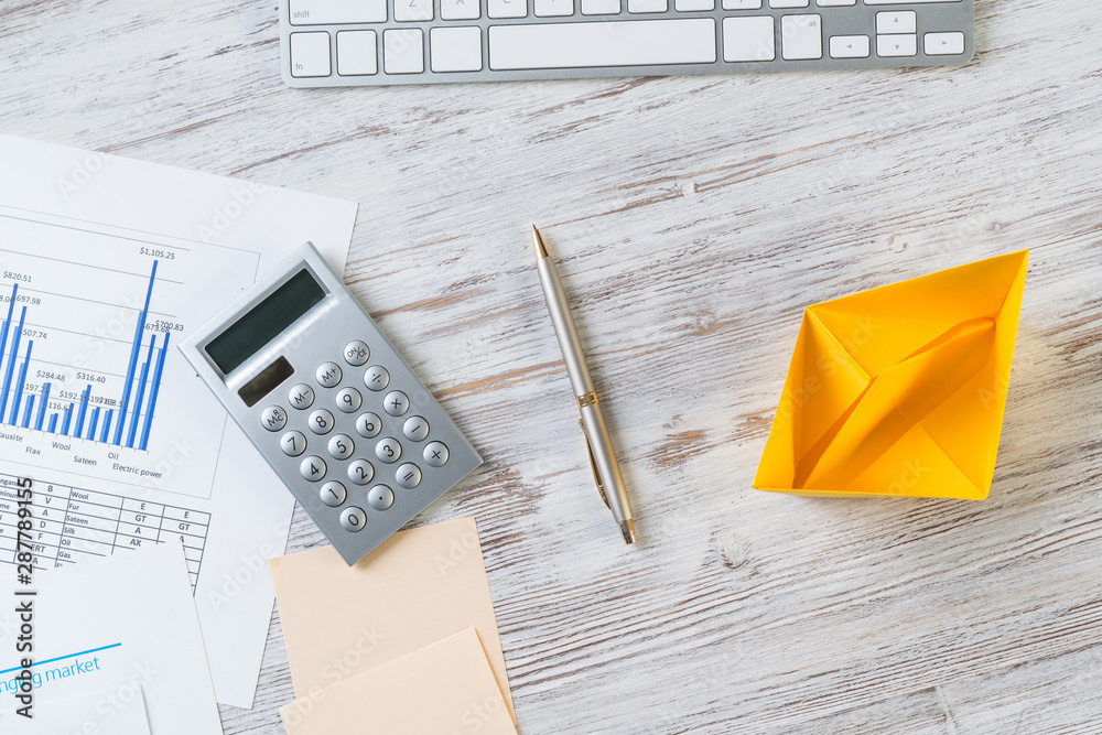 Workspace with office desk and yellow paper ship