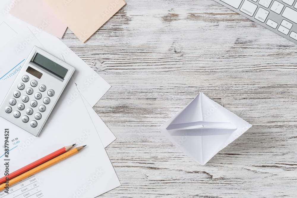 Wooden office desk with white origami boat.