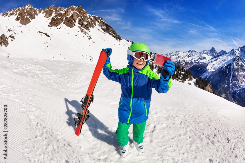 Happy boy hold ski taking picture with smartphone