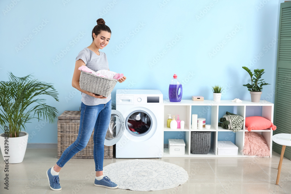 Beautiful young woman doing laundry at home