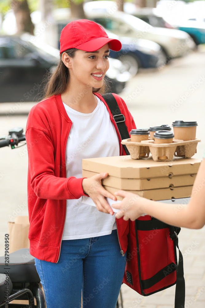 Woman taking order from courier of food delivery service outdoors