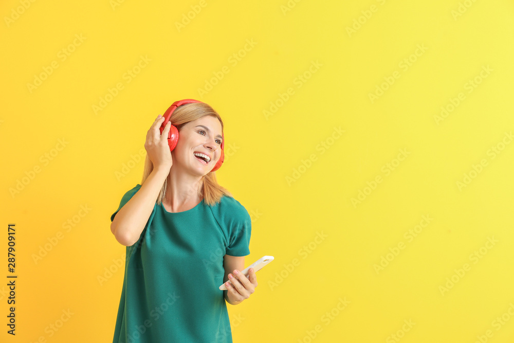 Happy beautiful woman listening to music on color background