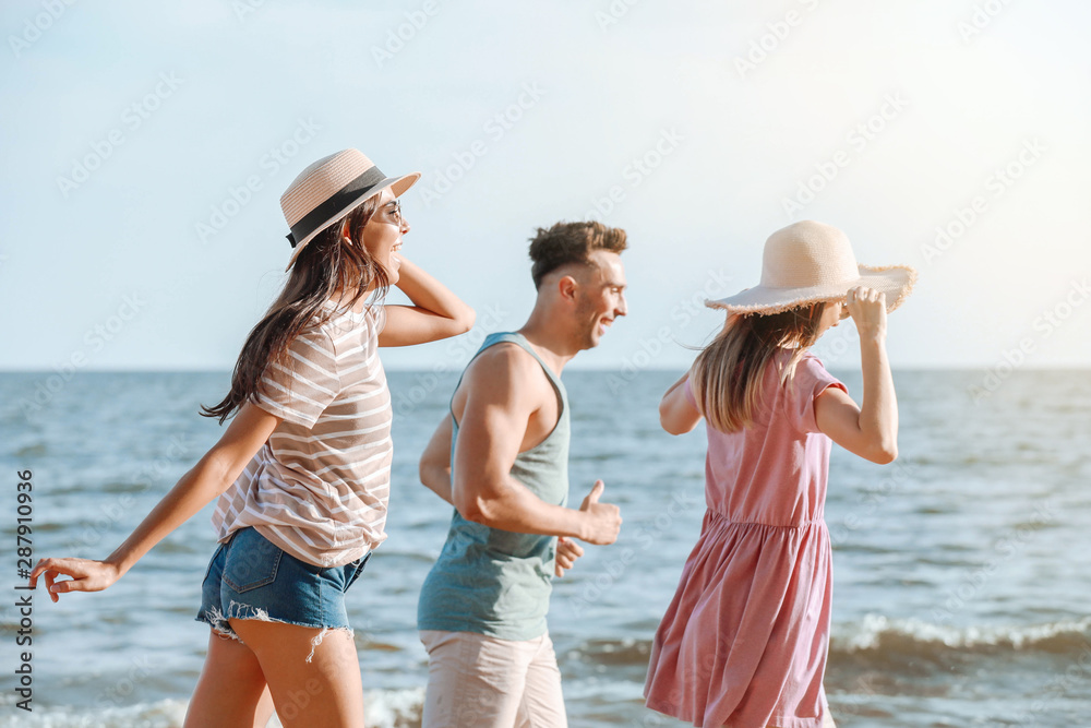 Happy friends running on sea beach at resort