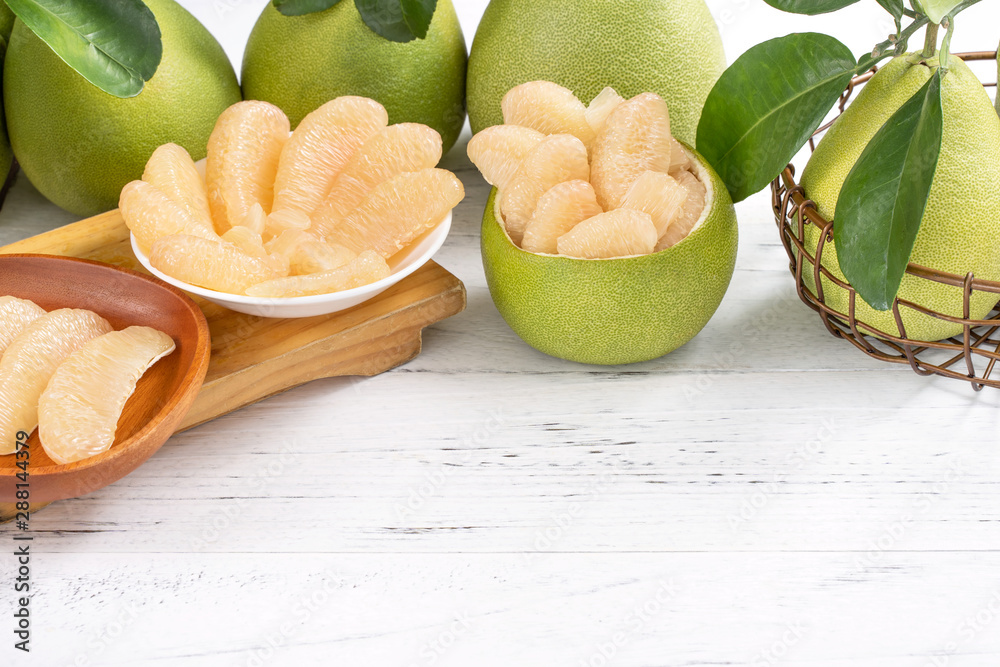 Fresh peeled pomelo, grapefruit, shaddock on bright wooden table background. Seasonal fruit for Mid-