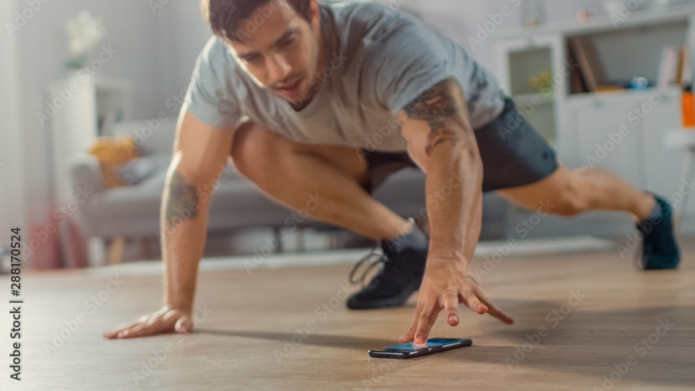 Muscular Athletic Fit Man in T-shirt and Shorts is Doing Mountain Climber Exercises While Using a St