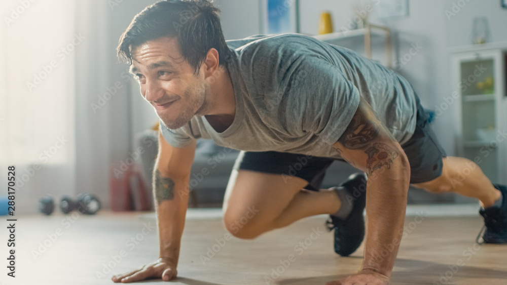 Muscular Athletic Fit Man in T-shirt and Shorts is Doing Mountain Climber Exercises While Using a St