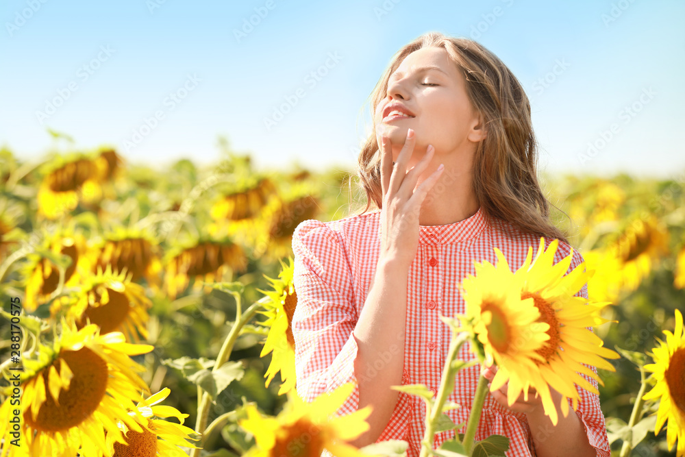 Beautiful young woman in sunflower field on summer day