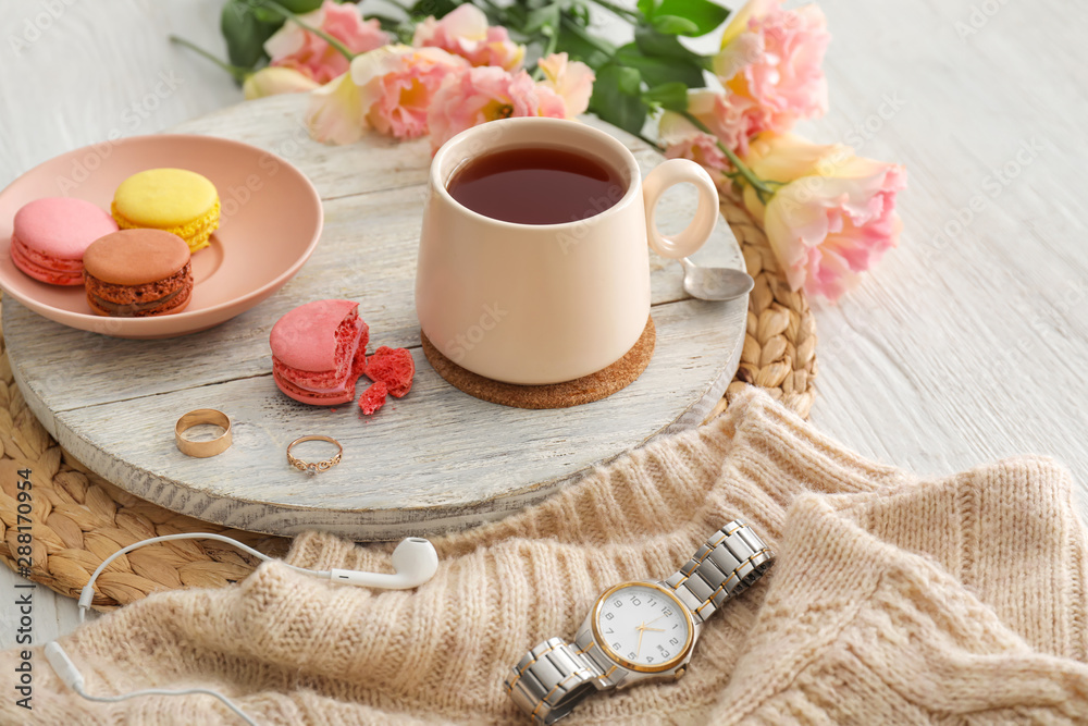 Cup of hot tea, flowers and macarons on table