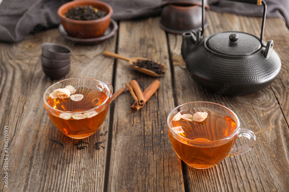 Cups of hot tea with cinnamon on wooden table