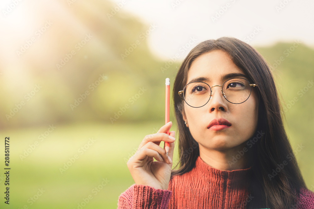 Young creative student girl thinking or planning future education while holding pencil in hand. Crea