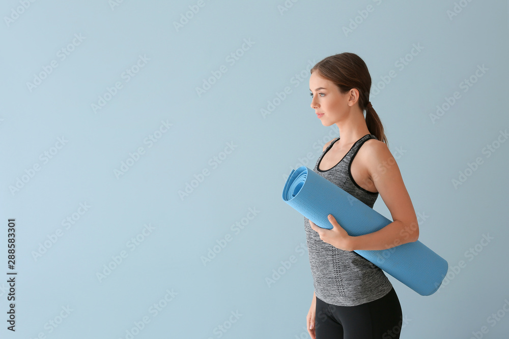 Young woman with yoga mat on color background