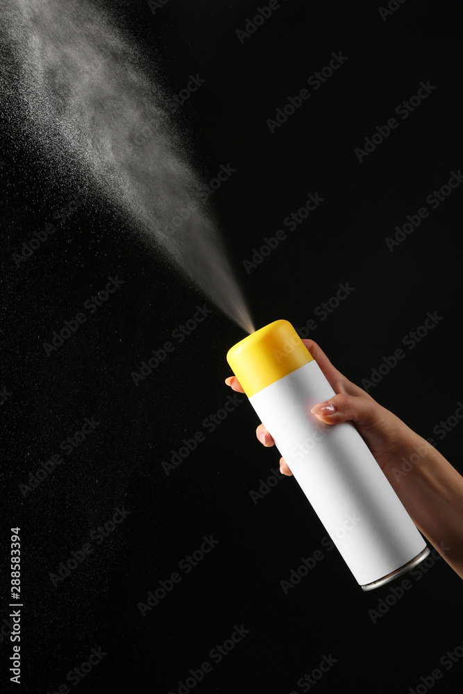 Female hand with bottle of air freshener on dark background