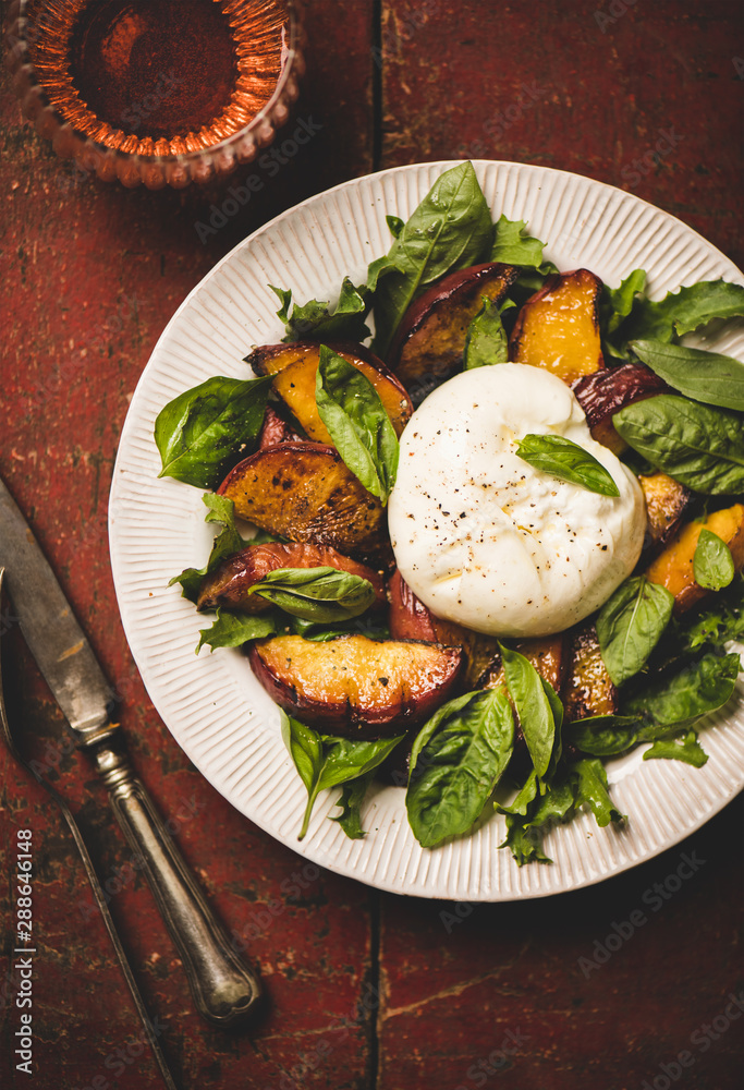 Flat-lay of seasonal salad with Burrata soft cheese and grilled peaches with glass of rose wine over