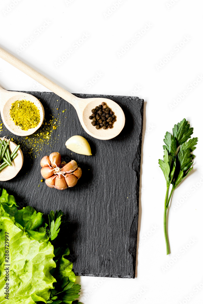 various spices in wooden spoons on white background top view