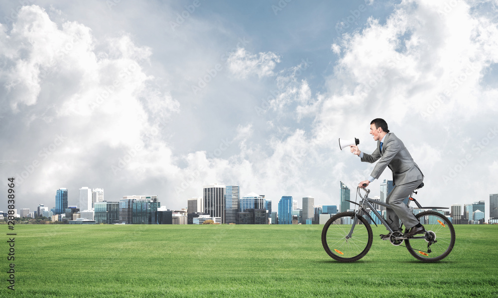 Businessman with megaphone on bike