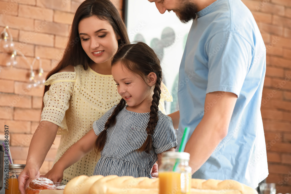 Young family with freshly baked buns in kitchen