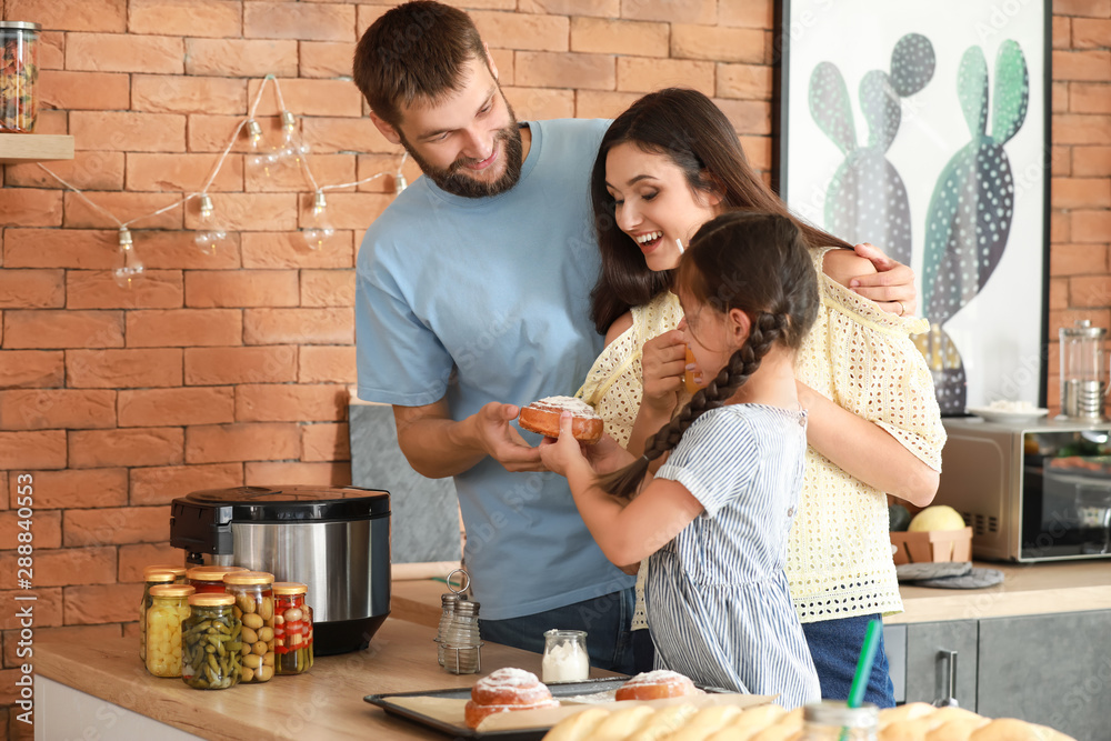 Young family with freshly baked buns in kitchen