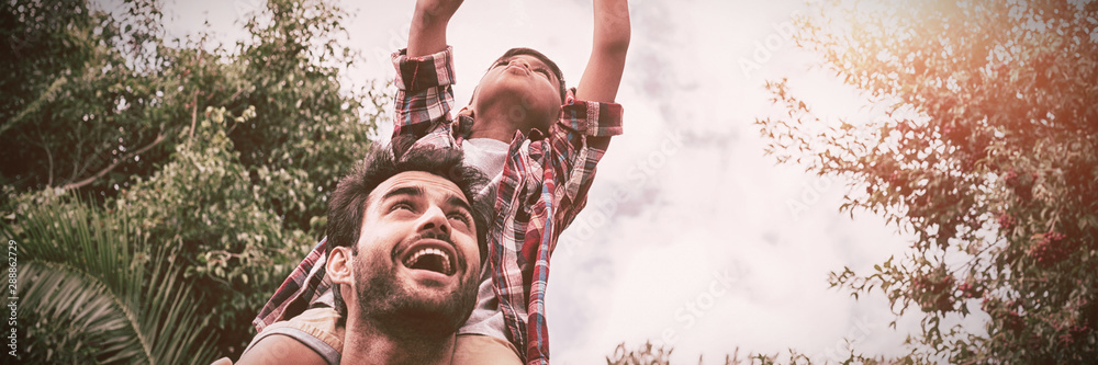 Low angle view of father carrying son playing with airplane