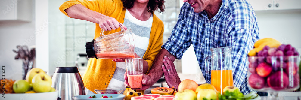 Happy couple preparing smoothie in kitchen