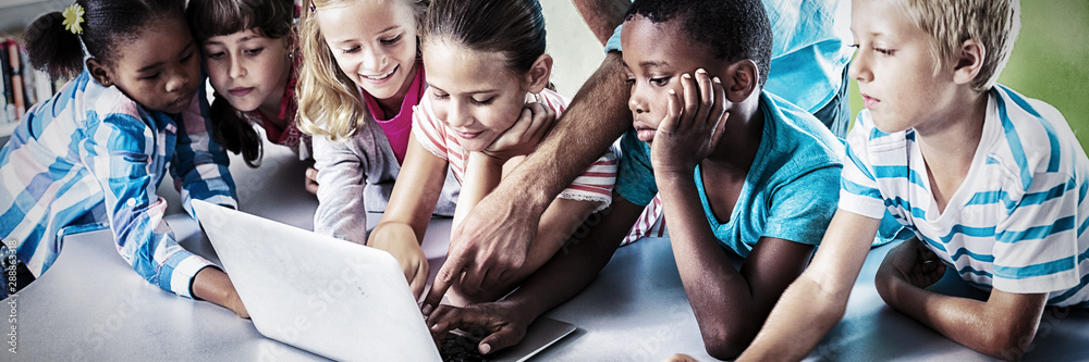 Teacher and children using laptop in library