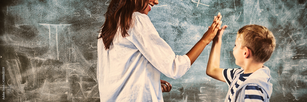 Teacher and boy giving high five in classroom