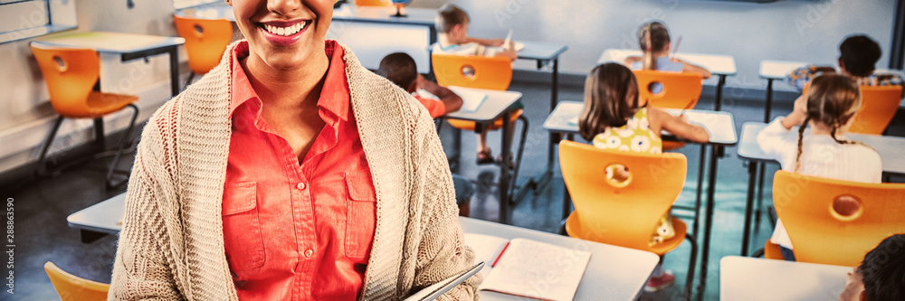 Portrait of teacher with tablet in classroom