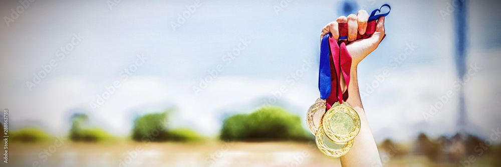 Hand of female athlete holding gold medals