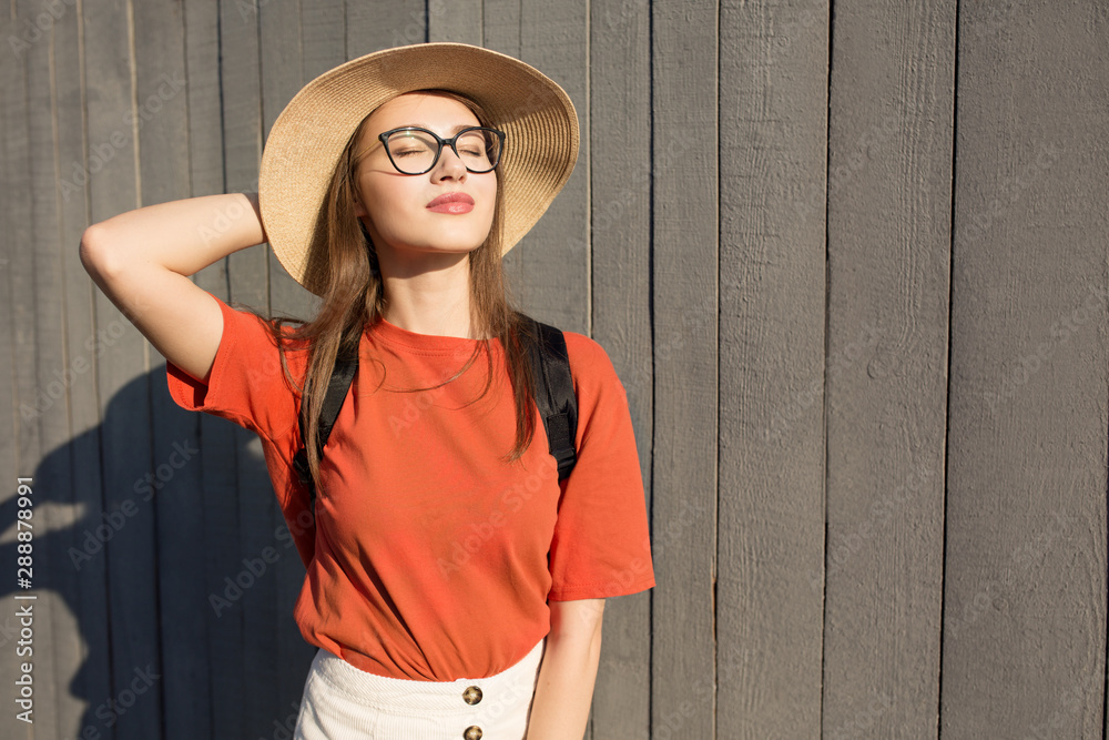 一个戴着智能手机的漂亮微笑女人的时尚肖像。靠着木墙