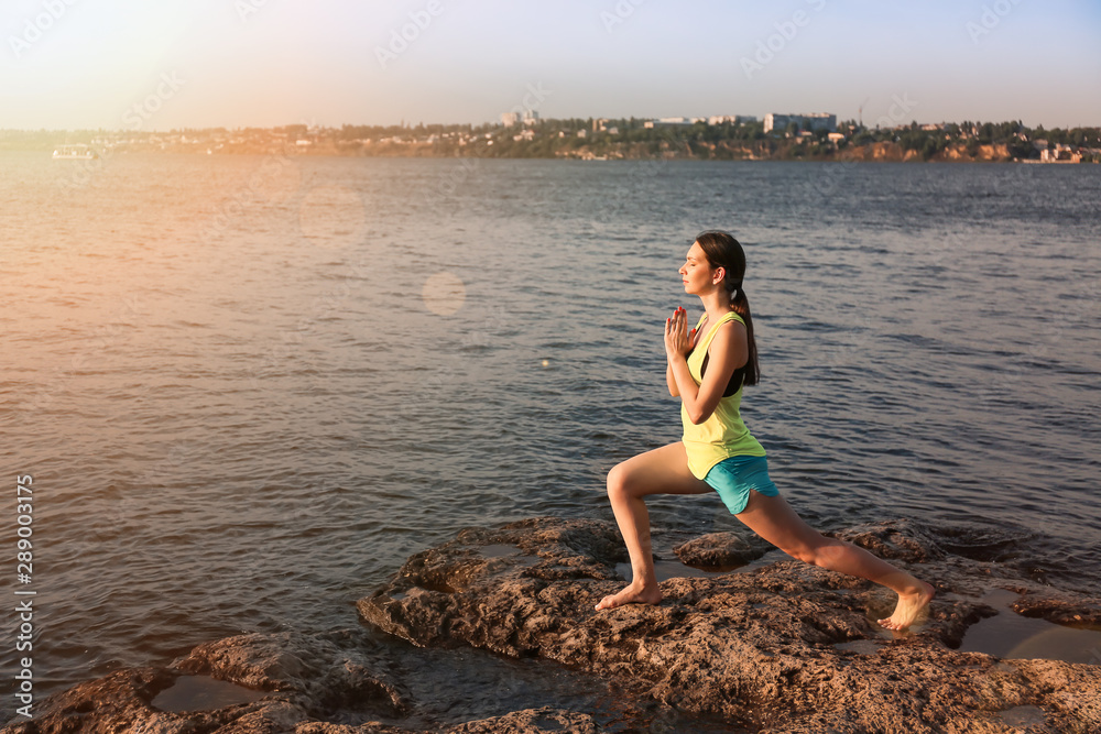 Young woman practicing yoga near river