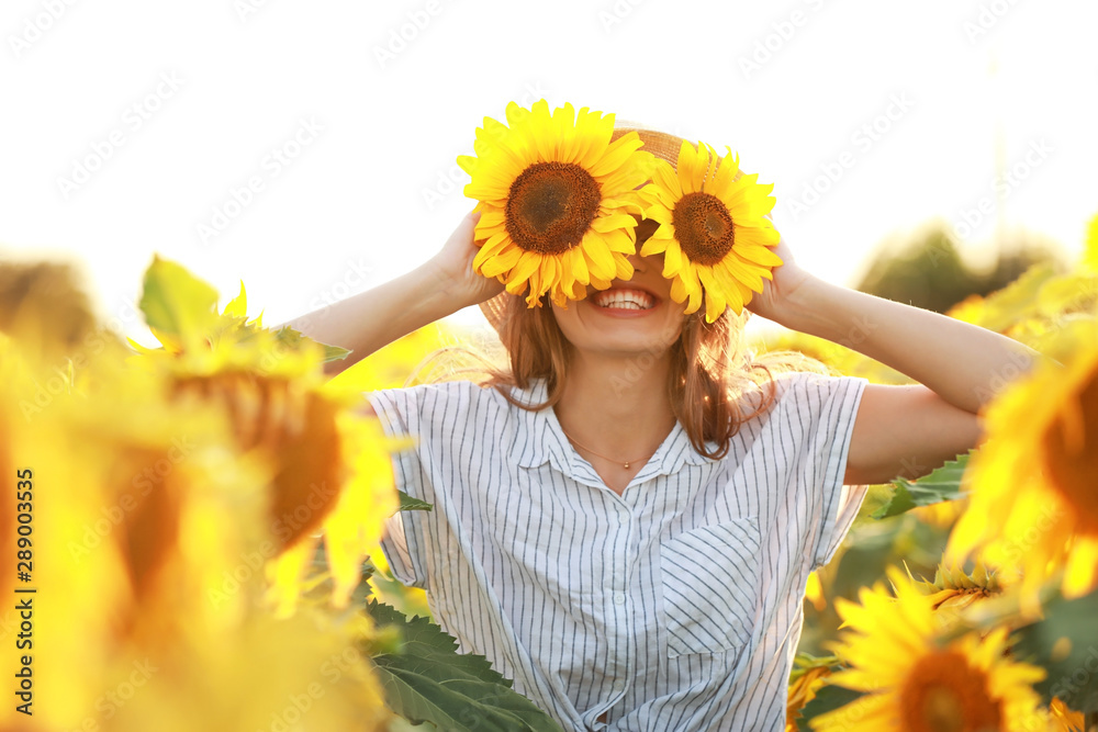 Beautiful young woman in sunflower field on summer day