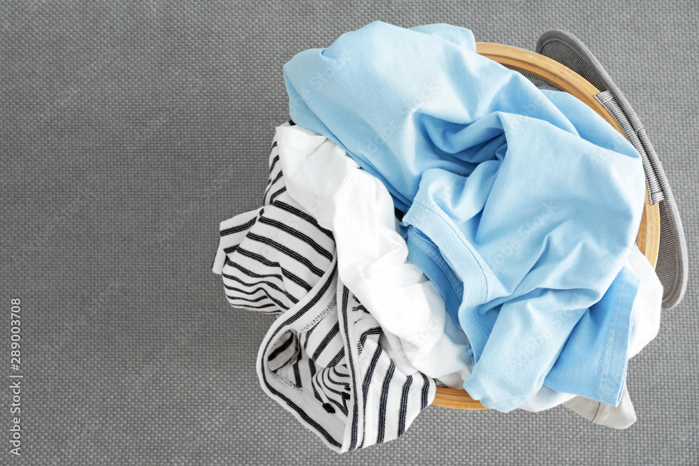 Basket with dirty laundry on grey background