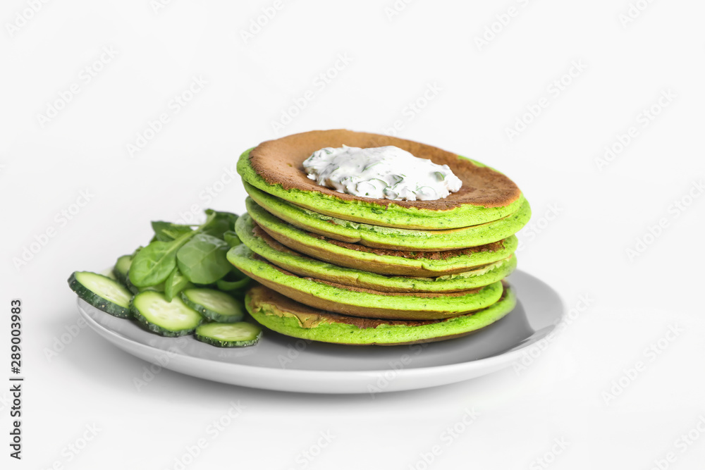 Tasty green pancakes with cucumber and sauce on white background