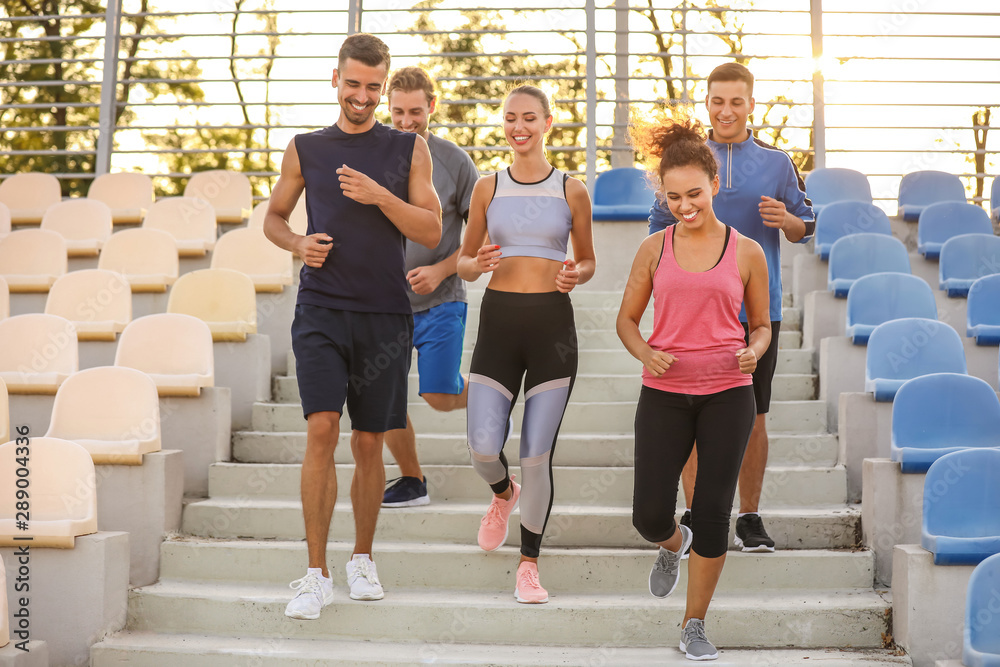 Group of sporty young people training at the stadium