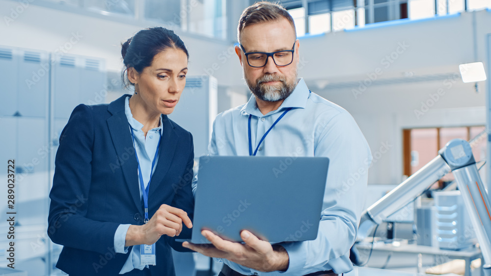 Female Chief Engineer Talks with Male Electronics Specialist, Explaining Things, He Holds on Laptop 